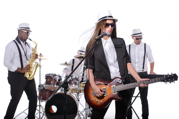 Foto banda de músicos com instrumentos no quarto branco.