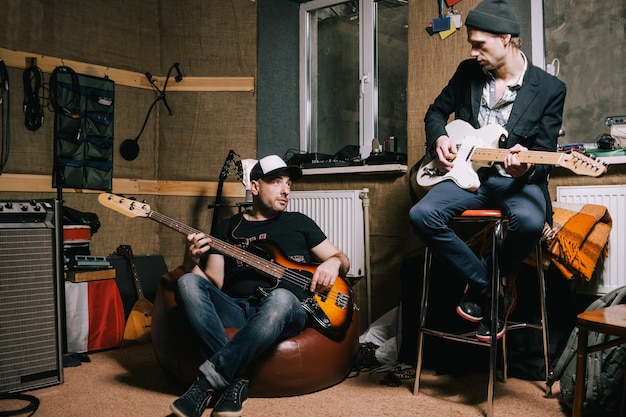 Banda de guitarristas adultos ensayando en el garaje