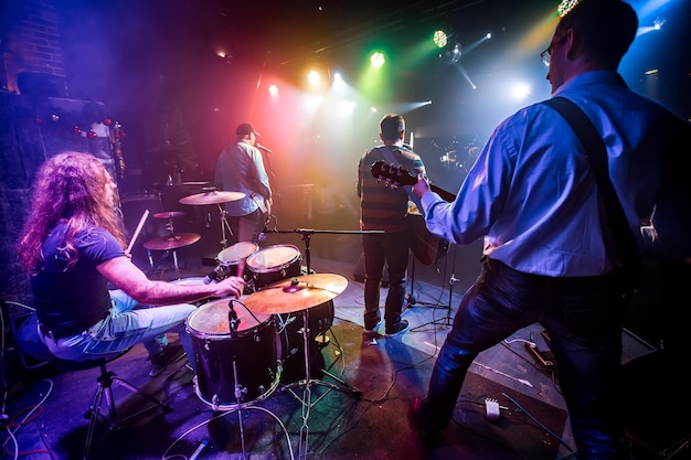 Banda se apresenta no palco, concerto de música rock em uma boate. disparo autêntico com alto iso em condições de iluminação desafiadoras. um pouco de grão e efeitos de movimento borrado.