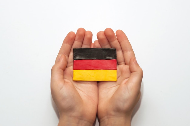 Bandeira alemã feita de plasticina nas mãos de uma criança em um fundo branco