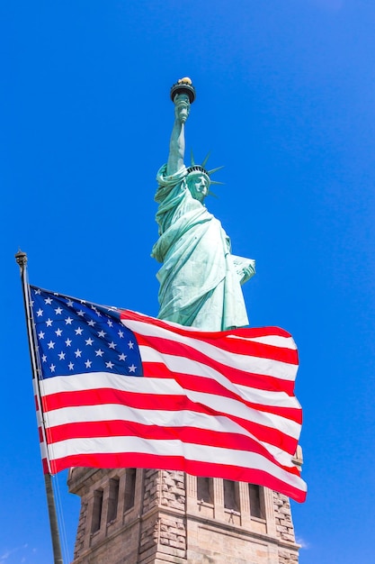 Bandeira americana balançando ao vento contra a Estátua da Liberdade