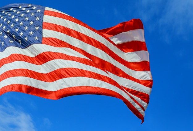 Bandeira americana vermelha, branca e azul com estrelas e tiras no céu azul do vento