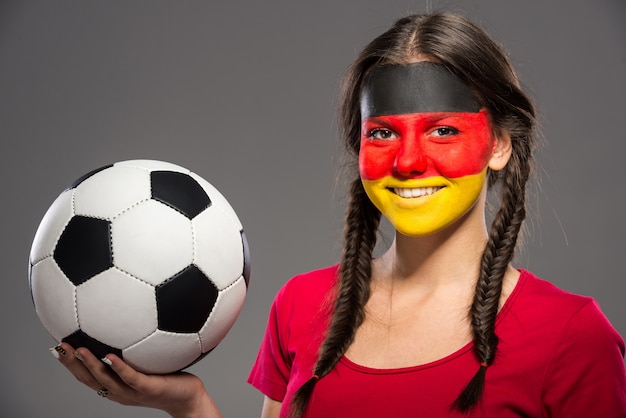 Bandeira da Alemanha pintado em um rosto de uma jovem mulher.