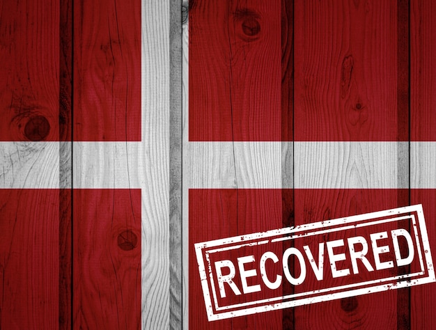Bandeira da Dinamarca que sobreviveu ou se recuperou das infecções da epidemia do vírus corona ou coronavírus. Bandeira do grunge com selo recuperado