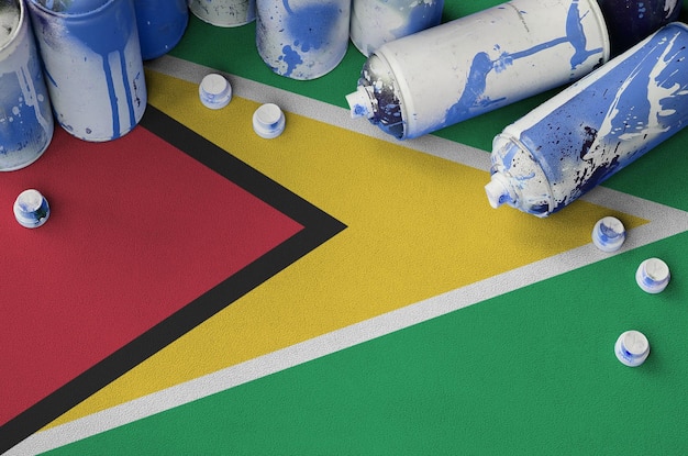 Bandeira da Guiana e algumas latas de spray de aerossol usadas para pintura de grafite Conceito de cultura de arte de rua