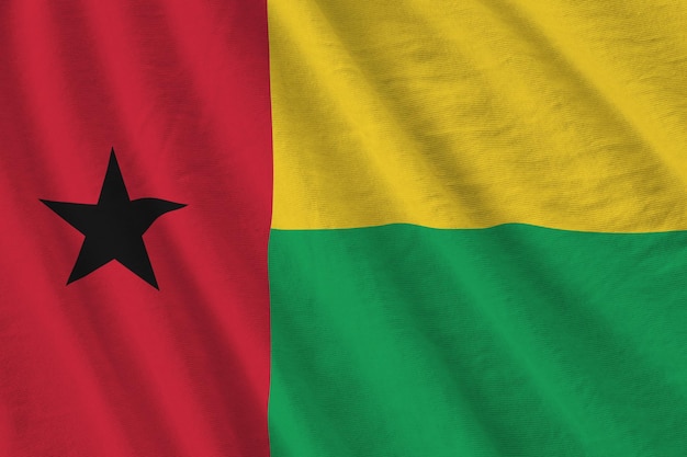 Bandeira da Guiné-Bissau com grandes dobras acenando sob a luz do estúdio dentro de casa Os símbolos oficiais e cores no banner