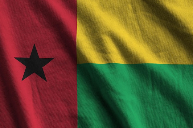 Bandeira da Guiné-Bissau com grandes dobras acenando sob a luz do estúdio dentro de casa Os símbolos oficiais e cores no banner