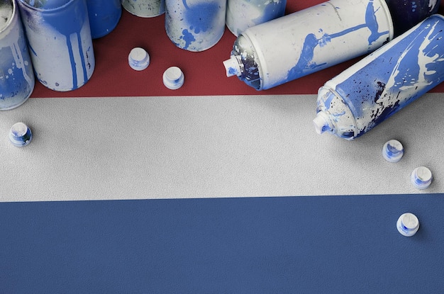 Bandeira da Holanda e poucas latas de aerossol usadas para pintura de grafite Conceito de cultura de arte de rua