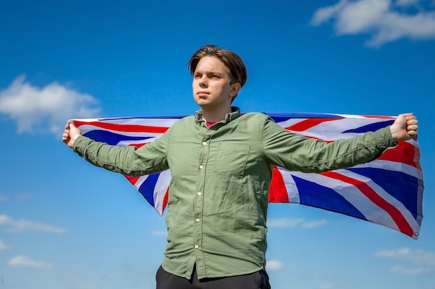 Bandeira da Inglaterra, jovem segurando uma grande bandeira da Inglaterra contra o céu