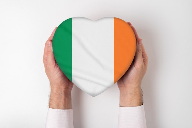 Bandeira da Irlanda em uma caixa em forma de coração nas mãos masculinas. fundo branco