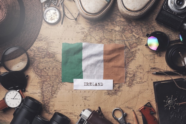 Bandeira da Irlanda entre acessórios do viajante no mapa antigo do vintage. Tiro aéreo