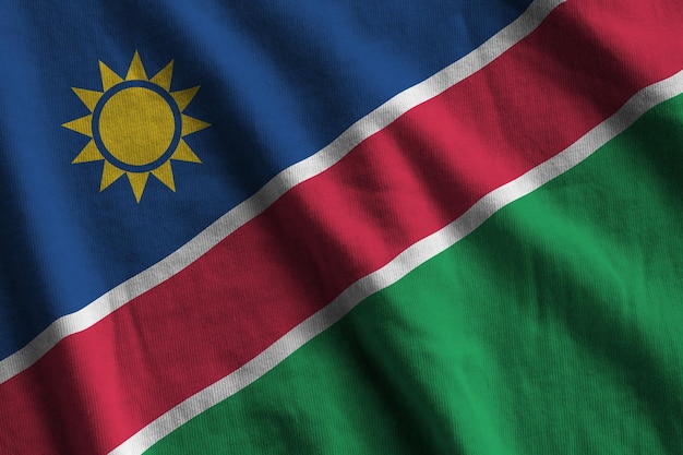 Bandeira da Namíbia com grandes dobras acenando de perto sob a luz do estúdio dentro de casa Os símbolos e cores oficiais no banner
