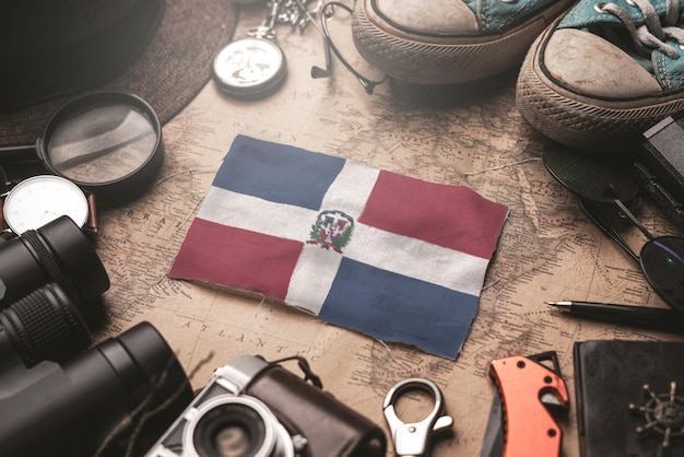 Bandeira da república dominicana entre acessórios do viajante no antigo mapa vintage. conceito de destino turístico.