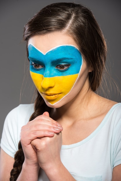 Bandeira da Ucrânia pintado no rosto da mulher bonita.