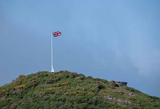 Bandeira da União e mastro no promontório contra o céu azul