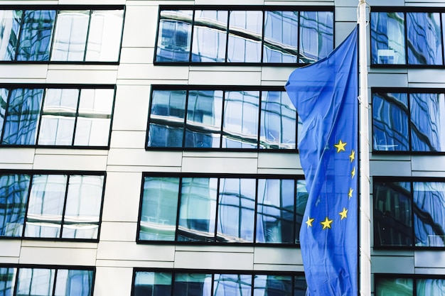 Bandeira da União Europeia acenando na frente do moderno edifício corporativo símbolo do parlamento da ue comm ...