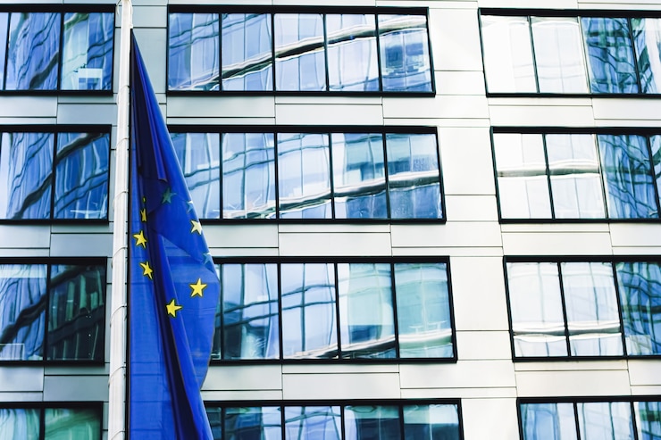 Foto bandeira da união europeia acenando na frente do moderno edifício de escritórios corporativos, símbolo do parlamento da ue com ...