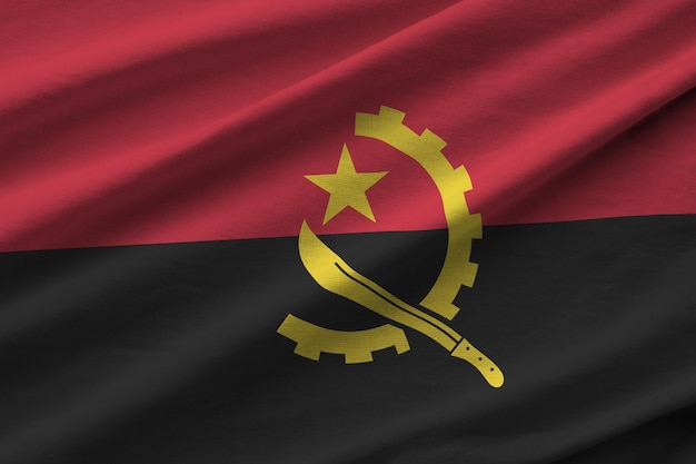 Foto bandeira de angola com grandes dobras acenando de perto sob a luz do estúdio dentro de casa os símbolos oficiais e cores no banner