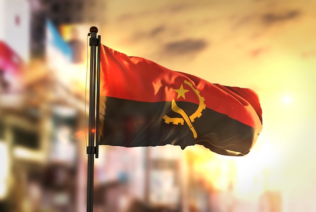 Bandeira de Angola contra a cidade Fundo borrado no amanhecer Luz de fundo