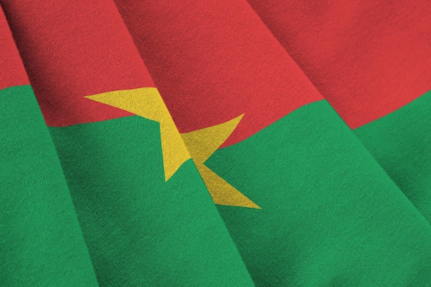 Bandeira de Burkina Faso com grandes dobras acenando de perto sob a luz do estúdio dentro de casa Os símbolos oficiais e cores no banner