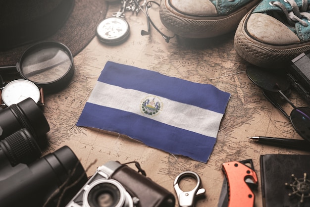 Bandeira de el salvador entre acessórios do viajante no antigo mapa vintage. conceito de destino turístico.