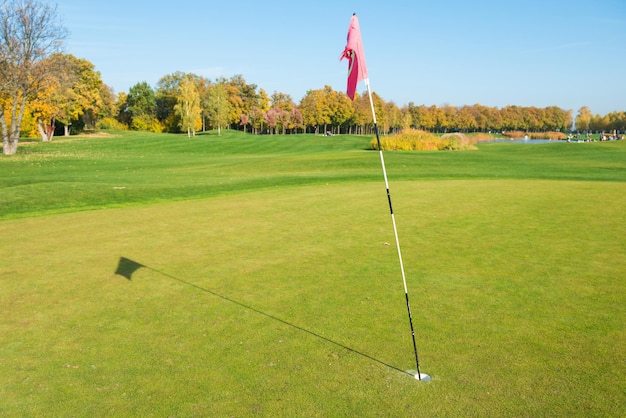 Bandeira de golfe perto de armadilha no campo de golfe verde