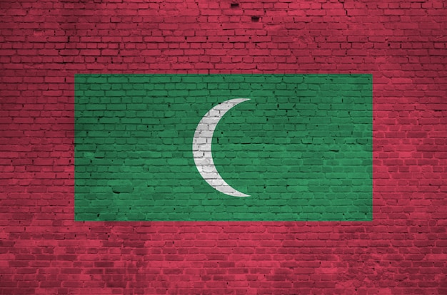 Bandeira de Maldivas retratada em cores de tinta na parede de tijolos antigos.