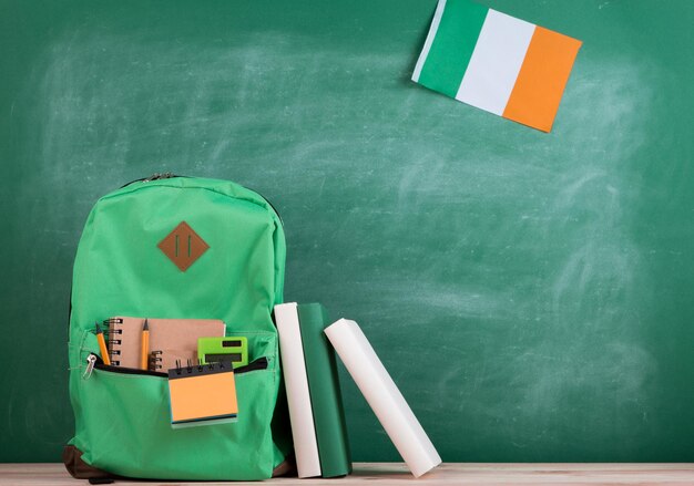 Bandeira de mochila verde dos livros e cadernos da Irlanda no fundo do quadro-negro