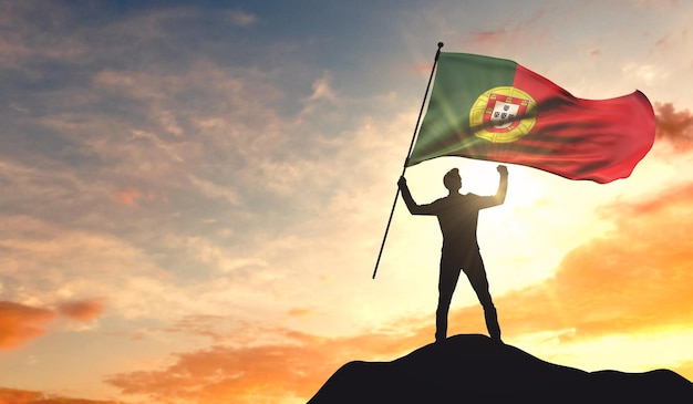 Bandeira de Portugal sendo acenada por um homem comemorando o sucesso no topo de uma montanha 3D Rendering