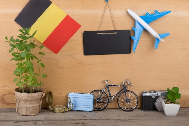 Bandeira de quadro-negro em branco do modelo de avião belga pequena bicicleta e bússola de câmera de mala