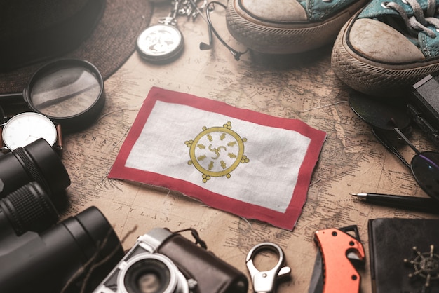 Foto bandeira de sikkim entre acessórios do viajante no antigo mapa vintage. conceito de destino turístico.