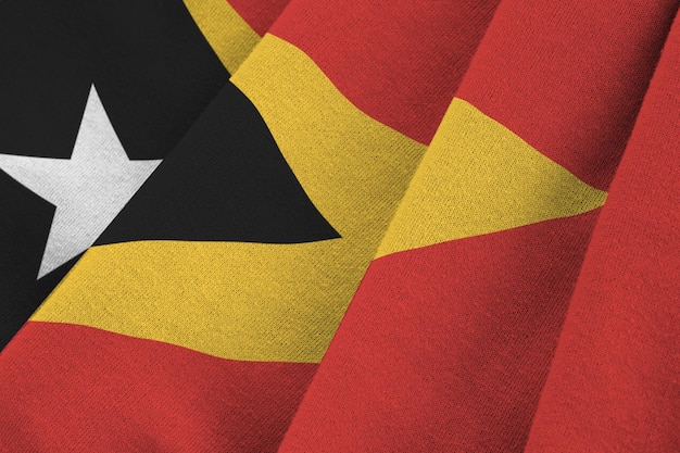 Bandeira de Timor-Leste com grandes dobras acenando de perto sob a luz do estúdio dentro de casa Os símbolos e cores oficiais no banner