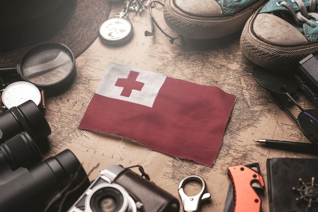 Bandeira de Tonga entre acessórios do viajante no mapa antigo do vintage. Conceito de destino turístico.