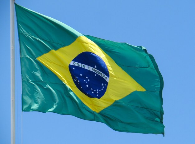 Bandeira do Brasil tremulando ao vento. No centro da bandeira com as palavras "ordem e progresso"
