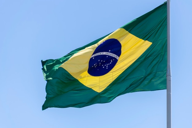 Bandeira do brasil tremulando no céu azul ordem e progresso na bandeira luso-brasileira