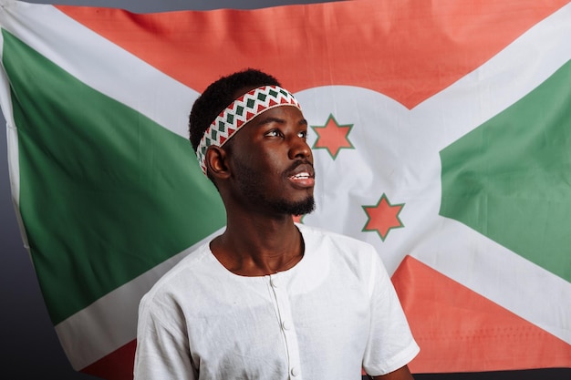 Bandeira do Burundi atrás do homem engraçado sorrindo e rindo e mostrando gesto como uma mão