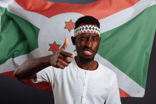 Bandeira do Burundi atrás do homem engraçado sorrindo e rindo e mostrando gesto como uma mão