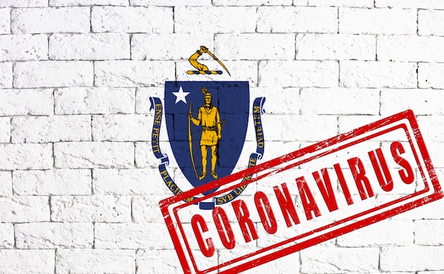 Bandeira do estado de Massachusetts pintada no fundo da parede de tijolo sujo. com carimbo CORONAVIRUS, ideia e conceito de saúde, epidemia e doença nos EUA