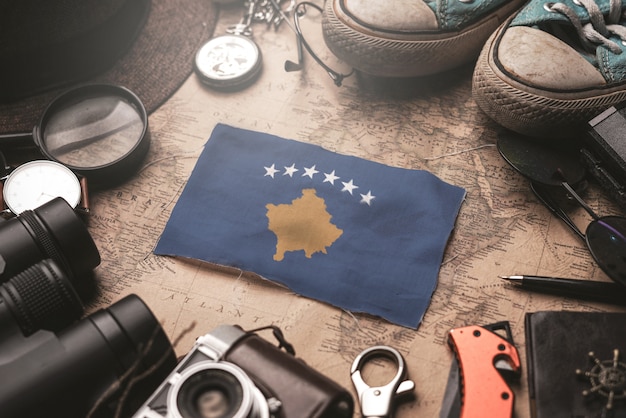 Bandeira do Kosovo entre acessórios do viajante no antigo mapa vintage. Conceito de destino turístico.