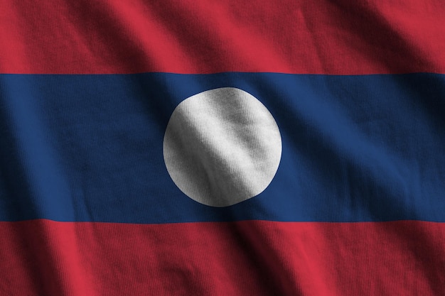 Bandeira do Laos com grandes dobras acenando de perto sob a luz do estúdio dentro de casa Os símbolos oficiais e cores no banner