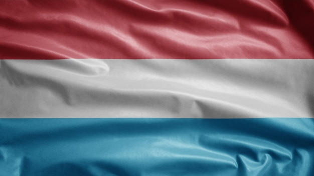 Bandeira do luxemburguês balançando ao vento. Perto da bandeira de Luxemburgo soprando, seda macia e suave. Fundo de estandarte de textura de tecido de pano.