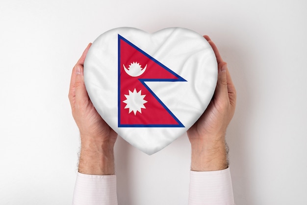 Bandeira do nepal em uma caixa em forma de coração nas mãos masculinas.