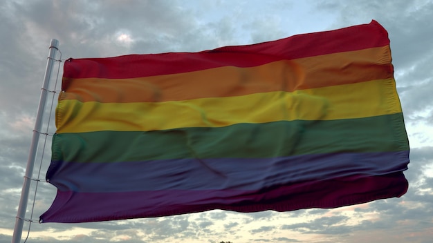 Bandeira do orgulho LGBT balançando ao vento contra um lindo céu profundo ao pôr do sol