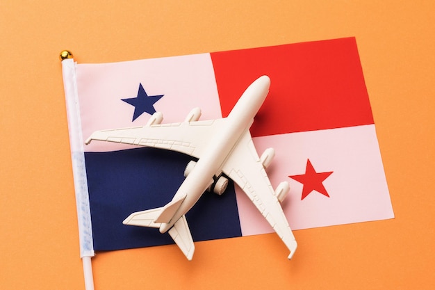 Bandeira do Panamá e avião de brinquedo em fundo laranja, conceito de voo do Panamá, vista superior