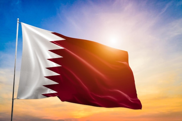 Bandeira do Qatar acenando e tremulando no sol espetacular brilhando através do fundo das nuvens