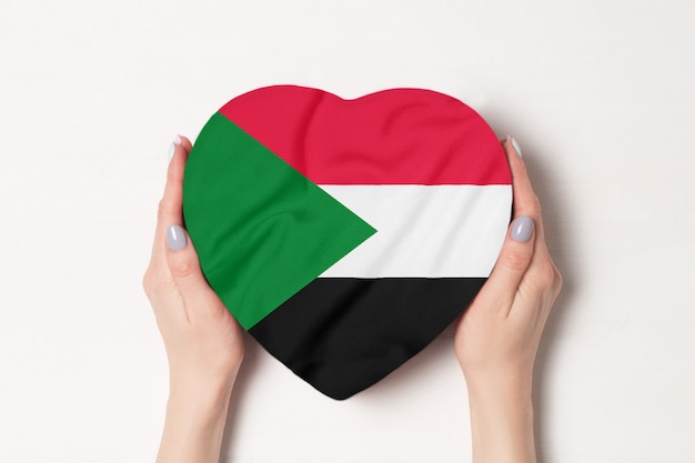 Bandeira do Sudão em uma caixa em forma de coração nas mãos femininas.