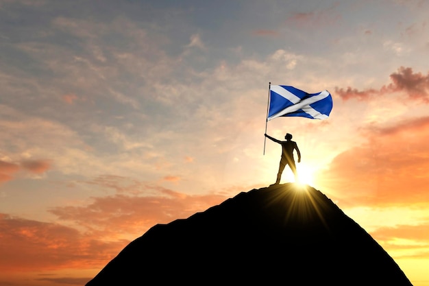 Bandeira escocesa sendo acenada no topo de um cume de montanha d renderização
