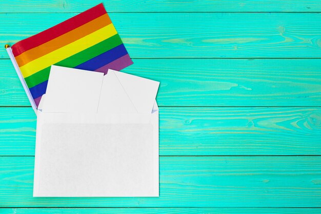 Bandeira gay de arco-íris brilhante no espaço em madeira e em branco