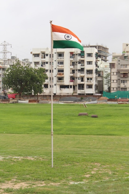 Foto bandeira indiana no campo contra edifícios