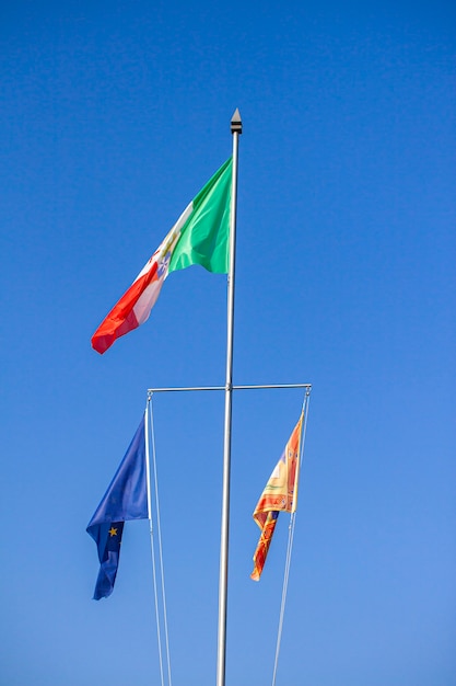 Bandeira italiana e europeia sob o céu azul no verão